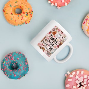 May include: White ceramic mug with the words "Teacher, Doctor, Therapist, Chef, Friend" and food-related illustrations. The mug is surrounded by colorful donuts with sprinkles on a light blue background.