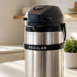 May include: A stainless steel coffee carafe with a black top and handle. The word "REGULAR" is printed in white on a black band around the carafe. The carafe is designed for keeping coffee hot.