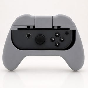 Op de afbeelding: Een grijze controller grip voor een gameconsole. De grip is ontworpen om een zwarte controller met de knoppen A, B, X en Y vast te houden. De grip heeft een gebogen ontwerp voor comfortabele bediening.