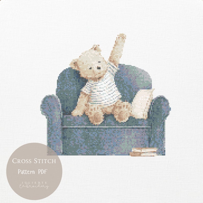 May include: A cross stitch pattern featuring a light brown teddy bear wearing a white t-shirt, sitting on a blue textured armchair with one arm raised. A small white pillow and a stack of books are beside the bear. Text reads Cross Stitch Pattern PDF.