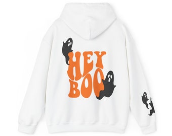 May include: White hoodie with the text "HEY BOO" in orange, with black ghost graphics. Additional ghost graphics are on the sleeve. A cozy, casual garment perfect for Halloween or spooky season.