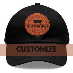 Peut inclure: Casquette de baseball noire avec un patch en cuir marron qui dit "Soutenez votre éleveur de boeuf local" et qui a une silhouette de vache. Le texte "Votre nom de ferme" est au centre du patch. La casquette a le mot "PERSONNALISER" sur le devant.