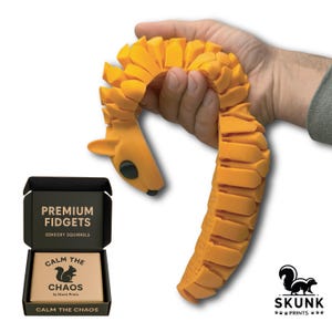Articulated Sensory Squirrel toy resting on a modern office desk near a coffee mug and small plant. Photographed with soft natural light, this full-size squirrel fidget blends into a professional environment as a premium desk toy. Provides lifelike sensory feedback, calming tactile play, and unique executive desk entertainment.