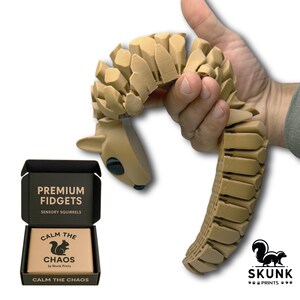 Sensory Squirrel toy resting naturally in an adult’s hand, with articulated segments draping like a real squirrel. Produces a gentle clicking sound and soothing tactile sensation, making it perfect for ASMR enthusiasts, fidget toy collectors, and adults seeking calming desk toys for stress and anxiety relief.