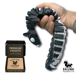 Sensory Squirrel fidget toy in playful motion, tail flipping upward when the hips are squeezed. The articulated diamond-pattern body flexes smoothly and creates a gentle ASMR clack sound. Designed as a unique stress-relief desk toy for adults, this full-size squirrel toy offers tactile sensory feedback and endless entertainment at work or home