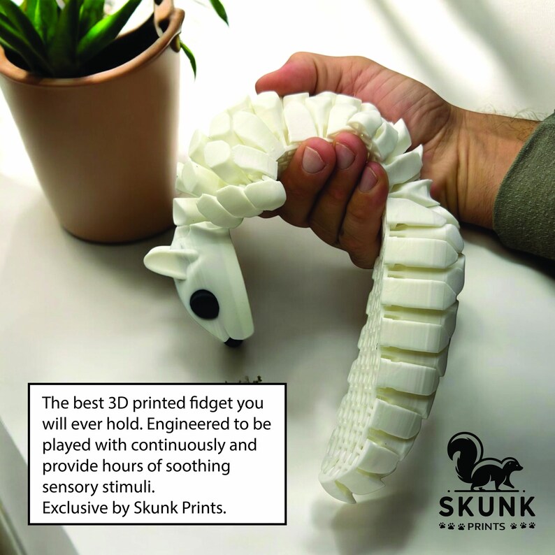 May include: A white 3D-printed fidget toy shaped like a stylized animal, held in a hand. The toy has a segmented body and a head with black eyes. Text on the image reads: "The best 3D printed fidget you will ever hold...Exclusive by Skunk Prints."