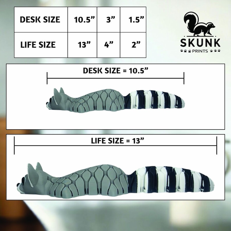 Op de afbeelding: Een grijs en wit wasbeer-vormig bureau-accessoire. De afbeelding toont twee maten: bureaumaat van 26,67 cm lang en levensgrootte van 33,02 cm lang. Het product is van Skunk Prints.