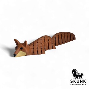 Person gently holding the HyperFlexi Fox demonstrating flexible movement and sensory relaxation for stress relief and focus — persona sosteniendo juguete antiestrés zorro articulado, alivio sensorial y concentración.