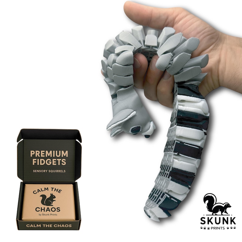 Closeup of a hand holding the articulated Sensory Squirrel desk toy, showing the lifelike flexible tail and chainmail-style body. This realistic squirrel-shaped fidget toy offers sensory feedback, weighted feel, and calming motion for adults and teens with ADHD, autism, or anyone who enjoys tactile toys. Premium design by Skunk Prints LLC
