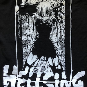 May include: Black and white graphic t-shirt featuring an anime character with the text "Hellsing" printed on the bottom.