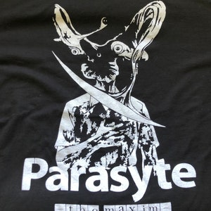 May include: Black t-shirt with a white graphic of a creature with large eyes and a blade. The word "Parasite" is printed in large white letters, with "the maxim" below.