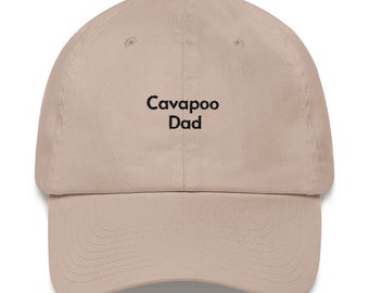 May include: A beige baseball cap with black embroidered text that reads "Cavapoo Dad".
