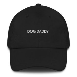 May include: A black baseball cap with white embroidered text that reads "DOG DADDY".
