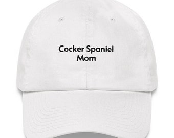 May include: White baseball cap with black embroidered text that reads "Cocker Spaniel Mom".