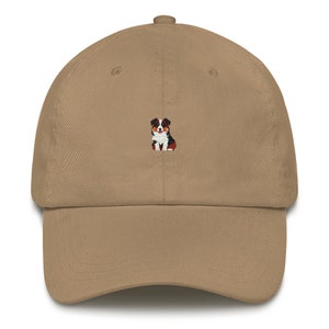 May include: A tan baseball cap with an embroidered image of an Australian Shepherd dog.