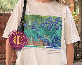May include: Ivory-colored t-shirt featuring a print of Van Gogh's "Irises" painting. The graphic includes the painting's title, artist's name, and color palette. The shirt is a relaxed fit.