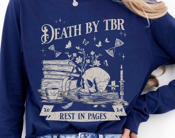 May include: Navy blue long-sleeved shirt with a skull and crossbones graphic and the text "Death by TBR Rest in Pages".
