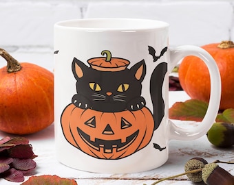 May include: White ceramic mug featuring a black cat inside an orange jack-o'-lantern. The mug has a handle and is decorated with bats. Pumpkins and fall foliage surround the mug, creating a Halloween theme.