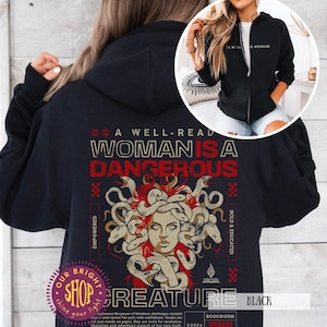 Op de afbeelding: Zwarte hoodie met ritssluiting met de tekst "A Well-Read Woman Is A Dangerous Creature" en een Medusa-afbeelding. Het ontwerp bevat de woorden "Empowered" en "Bold & Educated". Een kleinere afbeelding toont een vrouw die een vergelijkbare hoodie draagt.