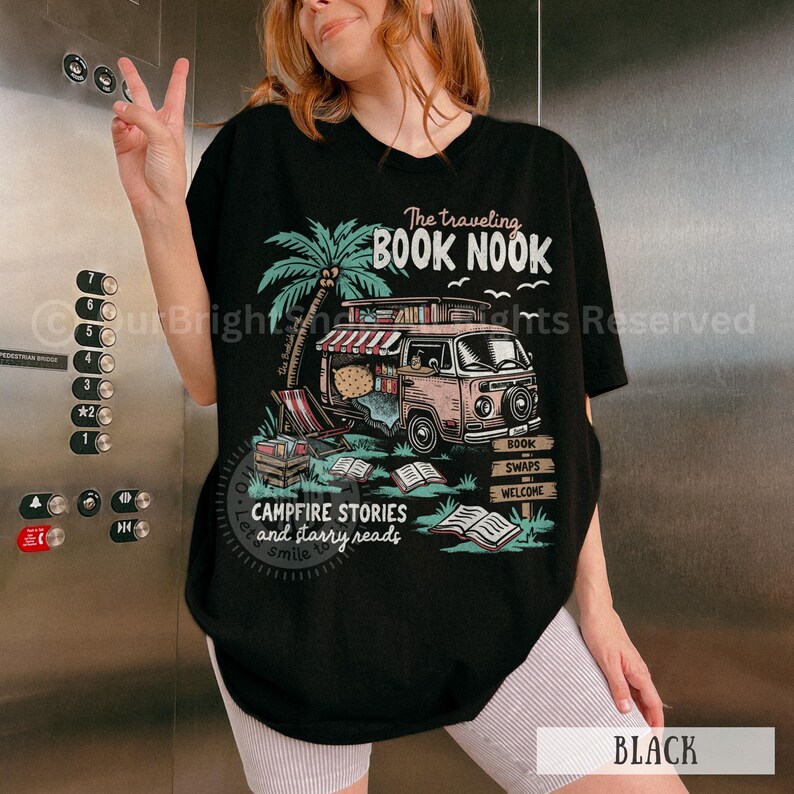 May include: Black t-shirt with a graphic of a vintage bookmobile with the text "The traveling BOOK NOOK" and "CAMPFIRE STORIES and starry reads".