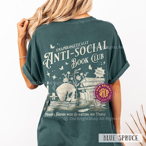 May include: Blue spruce t-shirt with the text "Unapologetically Anti-Social Book Club." The design features a skull, books, butterflies, and the phrase "Making Friends with Characters, Not People."