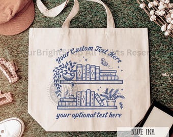 May include: A white canvas tote bag featuring a blue ink design of a bookshelf with books, plants, and a butterfly. The text "Your Custom Text Here" and "your optional text here" is printed on the bag.  BLUE INK SHOPPING TOTE is printed on the bottom of the bag.