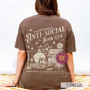 May include: Espresso-colored t-shirt with the text "UNAPOLOGETICALLY ANTI-SOCIAL BOOK CLUB" and a graphic of a skull, books, and flowers. The shirt also has the text "MAKING FRIENDS WITH CHARACTERS, NOT PEOPLE".
