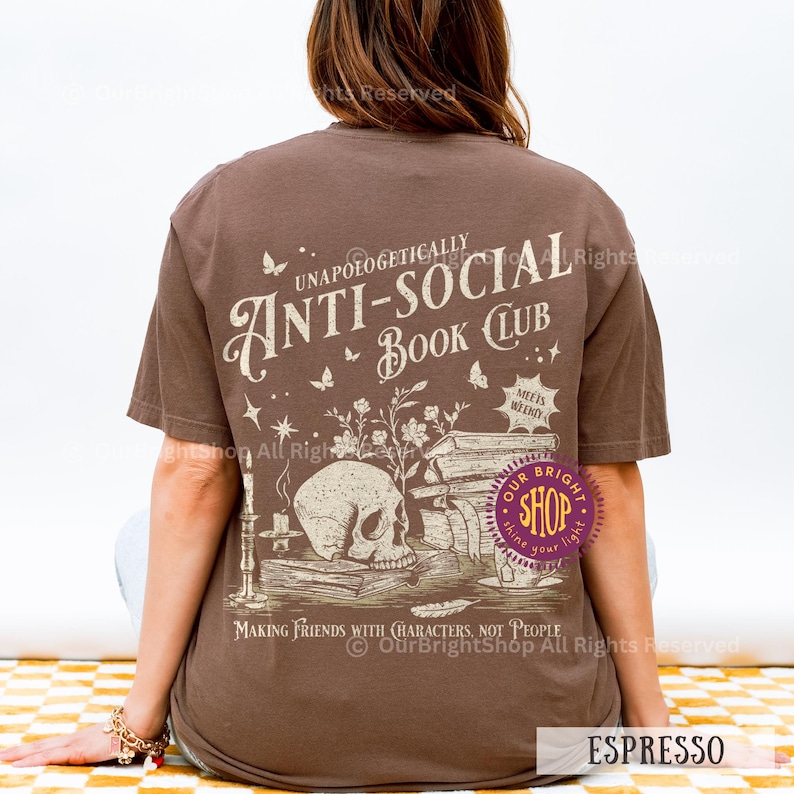 May include: Espresso-colored t-shirt with the text "UNAPOLOGETICALLY ANTI-SOCIAL BOOK CLUB" and a graphic of a skull, books, and flowers. The shirt also has the text "MAKING FRIENDS WITH CHARACTERS, NOT PEOPLE".
