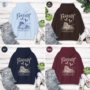 May include: Four hooded sweatshirts in different colors: light blue, dark chocolate, navy blue, and maroon. Each sweatshirt features a graphic print of a book with a dragon and the text "Once Upon a Time in the Fantasy Readers Society".