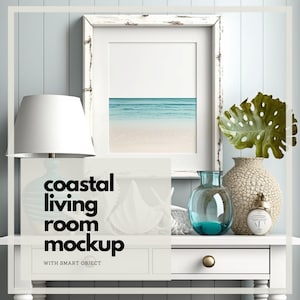 Op de afbeelding: Een mockup van een woonkamer aan de kust met een ingelijste strandprint, een witte lamp en decoratieve vazen. De tekst "coastal living room mockup" wordt weergegeven. De scène is geplaatst tegen een lichtblauwe muur.