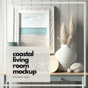 Puede incluir: Maqueta de salón costero con una escena de playa enmarcada, un jarrón blanco con plantas secas y conchas decorativas. El texto "coastal living room mockup" se muestra en la parte delantera. La escena está ambientada en una mesa azul claro y de madera.