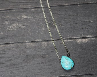 May include: A silver chain necklace with a turquoise teardrop pendant.
