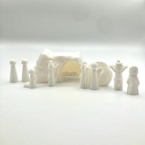 May include: A white plastic nativity scene set with a cave, angel, and figures of people.
