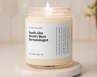 May include: A clear glass jar candle with a white label featuring black text that reads Smells Like World's Best Dermatologist, Scented Serenade, Hand-poured Soy Wax Candle, 50-60 Hours Burning Time, Eco-Friendly & Non-Toxic, KEEP THAT SHIT UP.