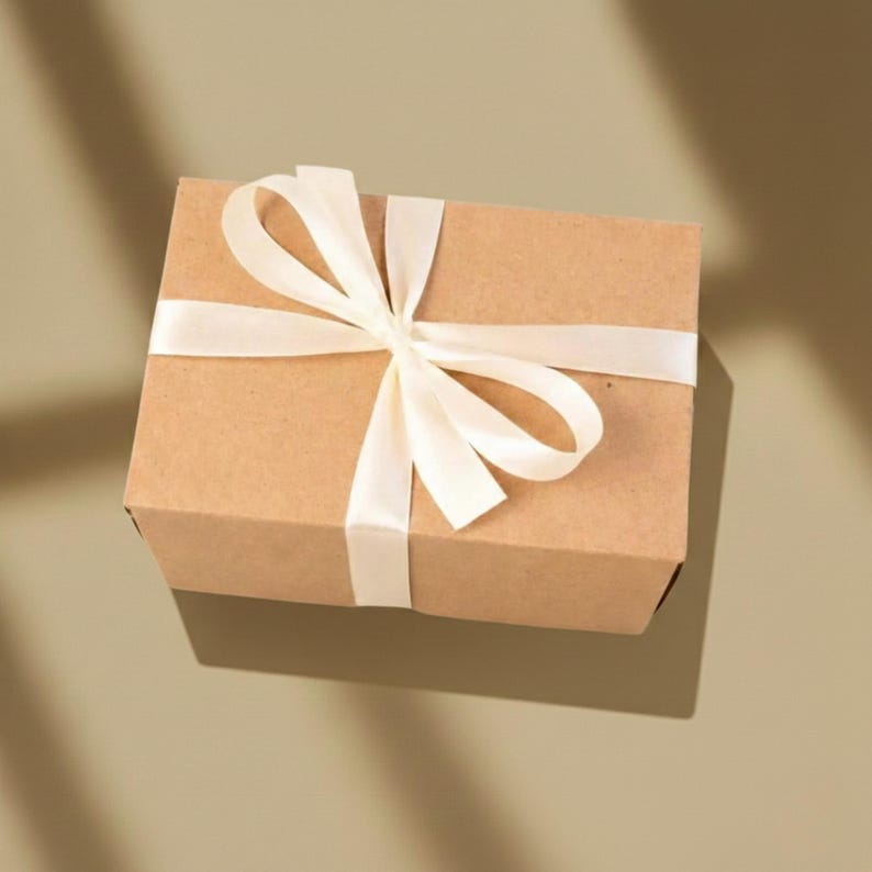 A brown cardboard box with a white ribbon tied around it, placed on a light-colored surface.