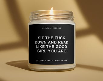Peut inclure: Une bougie en cire de soja dans un pot en verre transparent avec une mèche allumée. L'étiquette noire porte le texte blanc : SCENTED SERENADE, SIT THE FUCK DOWN AND READ LIKE THE GOOD GIRL YOU ARE, SOY WAX CANDLE | MADE IN USA.