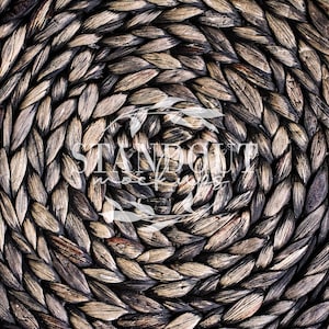 May include: Close-up of a woven circular mat made of natural fibers. The mat has a dark brown color and a textured surface. The fibers are woven in a circular pattern, creating a spiral effect.