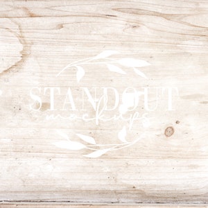 以下が含まれることがあります： 白い花の輪と「STANDOUT MOCKUPS」という白い文字が書かれた明るい木製の背景です。