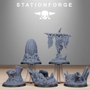 May include: A collection of gray miniature terrain pieces for tabletop gaming. The set includes a tall, oval-shaped structure, a scarecrow-like figure, and several organic-looking formations. The "STATIONFORGE" logo is at the top.