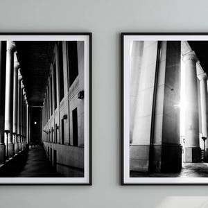 May include: Two framed black and white photographs. One shows a long corridor with columns and a dark perspective. The other depicts a row of columns with bright sunlight shining through. Both are architectural photography.