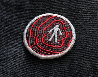 May include: A red and white embroidered patch with a white silhouette of a person walking inside concentric red circles.