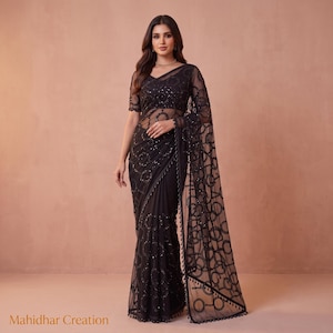 May include: A black saree featuring intricate circular embroidery patterns and scattered sequins throughout the fabric. The garment includes a matching short-sleeved blouse with a sheer neckline and a draped pallu with a decorative border.
