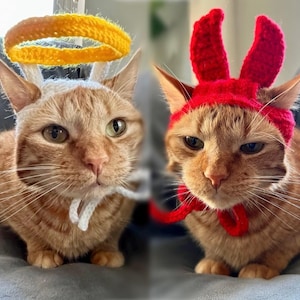 May include: Two orange tabby cats wearing crocheted hats. One cat is wearing a halo and the other is wearing a red lobster hat.