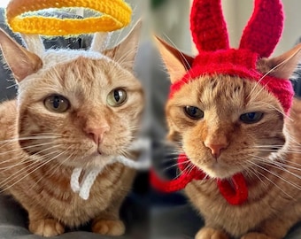 May include: Two orange tabby cats wearing crocheted hats. One cat is wearing a halo and the other is wearing a red lobster hat.