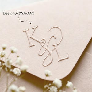 以下が含まれることがあります： セリフ体とスクリプト体を組み合わせたKとLの文字がアンパサンドで繋がれた、デボス加工のモノグラムが施されたライトベージュのカード。カードの左上隅にはDesign39(WA-AM)という文字が黒色で印刷されています。