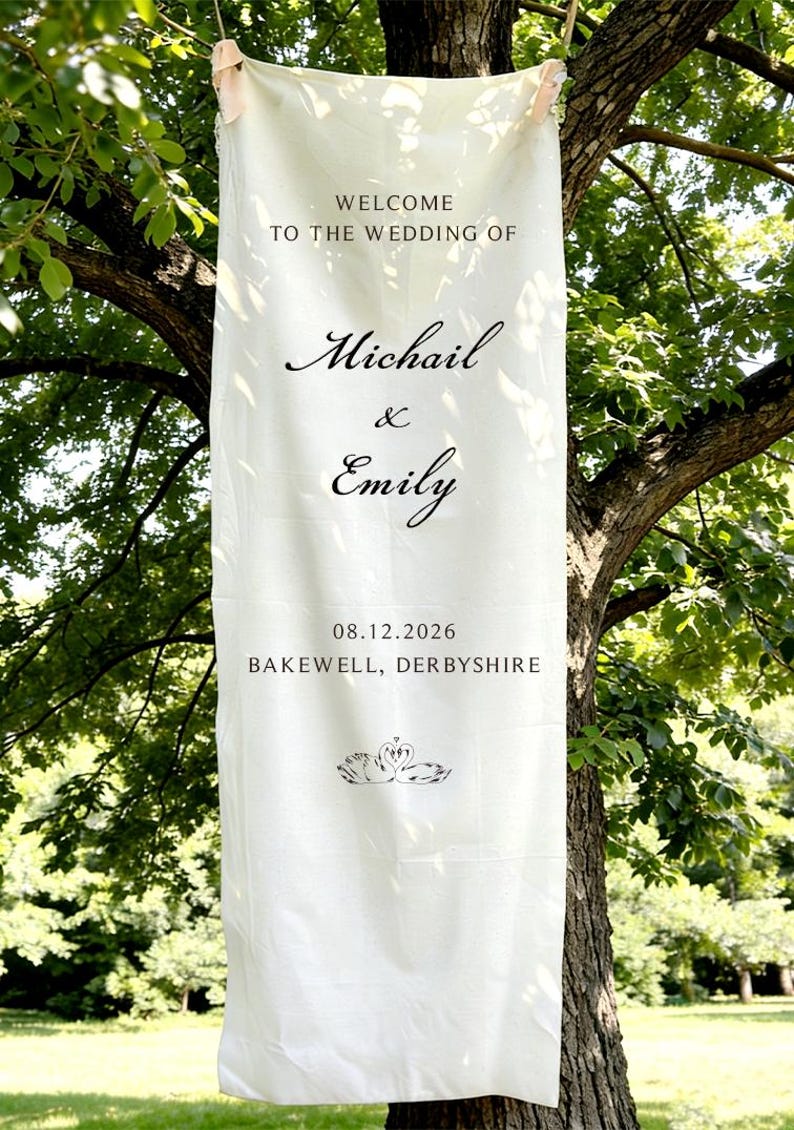 May include: A cream-colored wedding banner hanging from a tree. The banner reads "Welcome to the wedding of Michail & Emily" with the date 08.12.2026 and location Bakewell, Derbyshire. A swan graphic is at the bottom.
