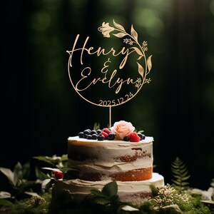 K&ouml;nnte beinhalten: Ein h&ouml;lzerner Hochzeitstortenaufsatz mit einem floralen Kranzdesign. Der Aufsatz tr&auml;gt die Namen "Henry & Evelyn" und das Datum "2025.12.24".