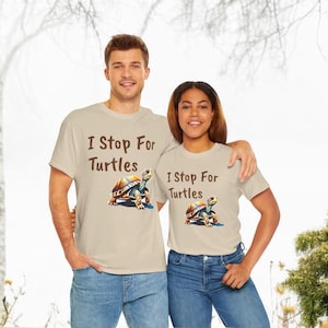 May include: Two people wearing beige t-shirts with a brown turtle graphic and the text "I Stop For Turtles".