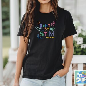 Pu&ograve; includere: Una maglietta nera con una grafica colorata che dice "Don't Stop the Stim" in un font divertente.