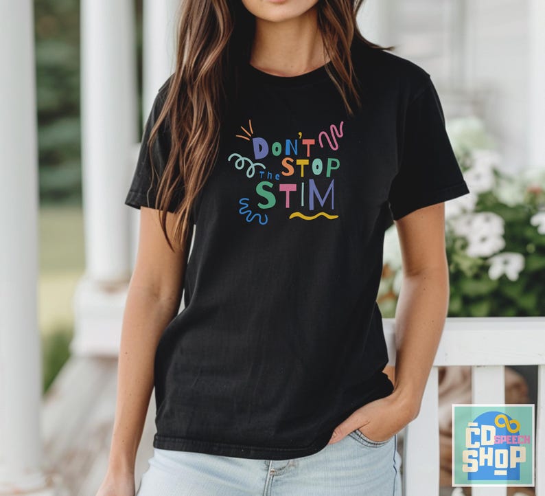 Pu&ograve; includere: Una maglietta nera con una grafica colorata che dice "Don't Stop the Stim" in un font divertente.